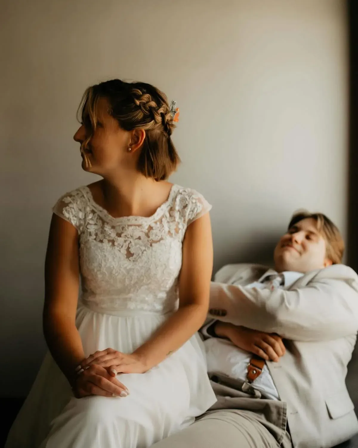 A newlywed couple sharing a quiet seated moment in warm window light